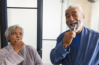 A man and woman brushing their teeth