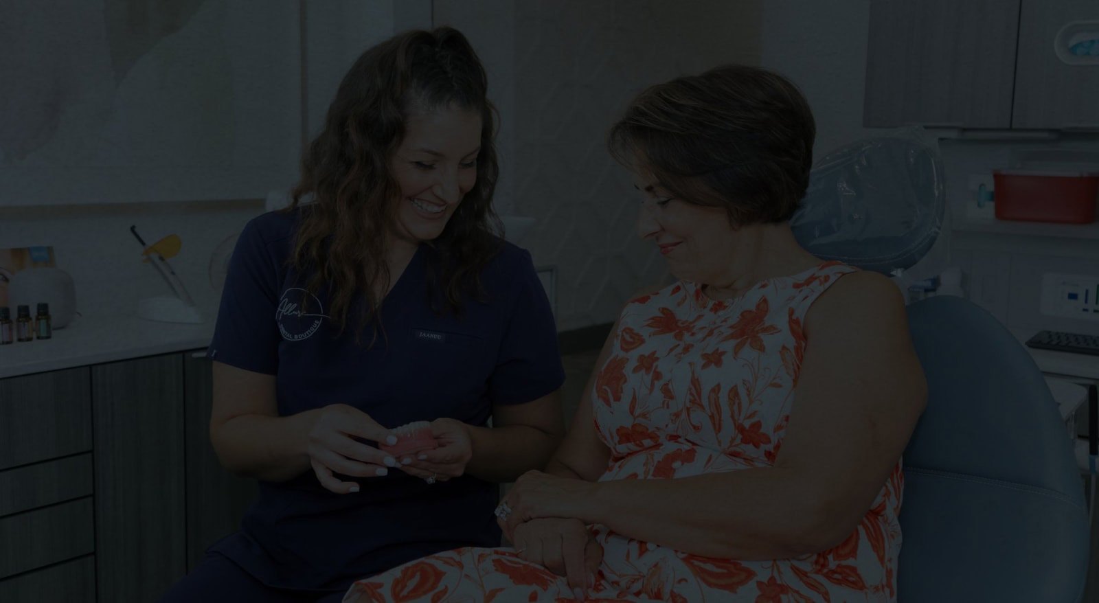 Smiling dental team member showing a denture to a patient