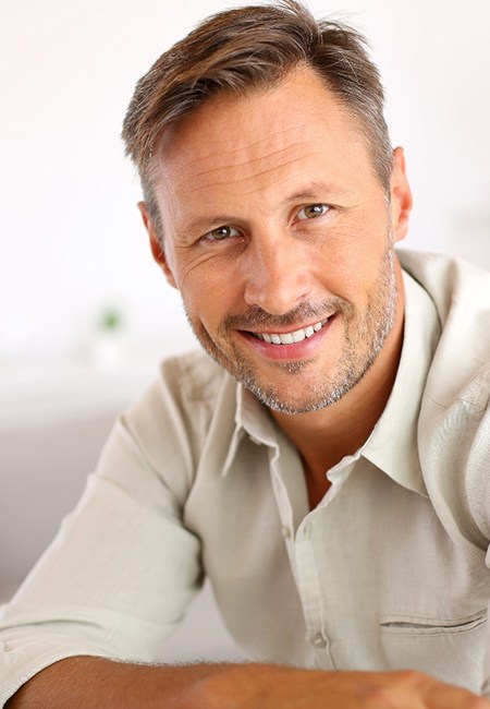 Man with facial hair sitting and smiling