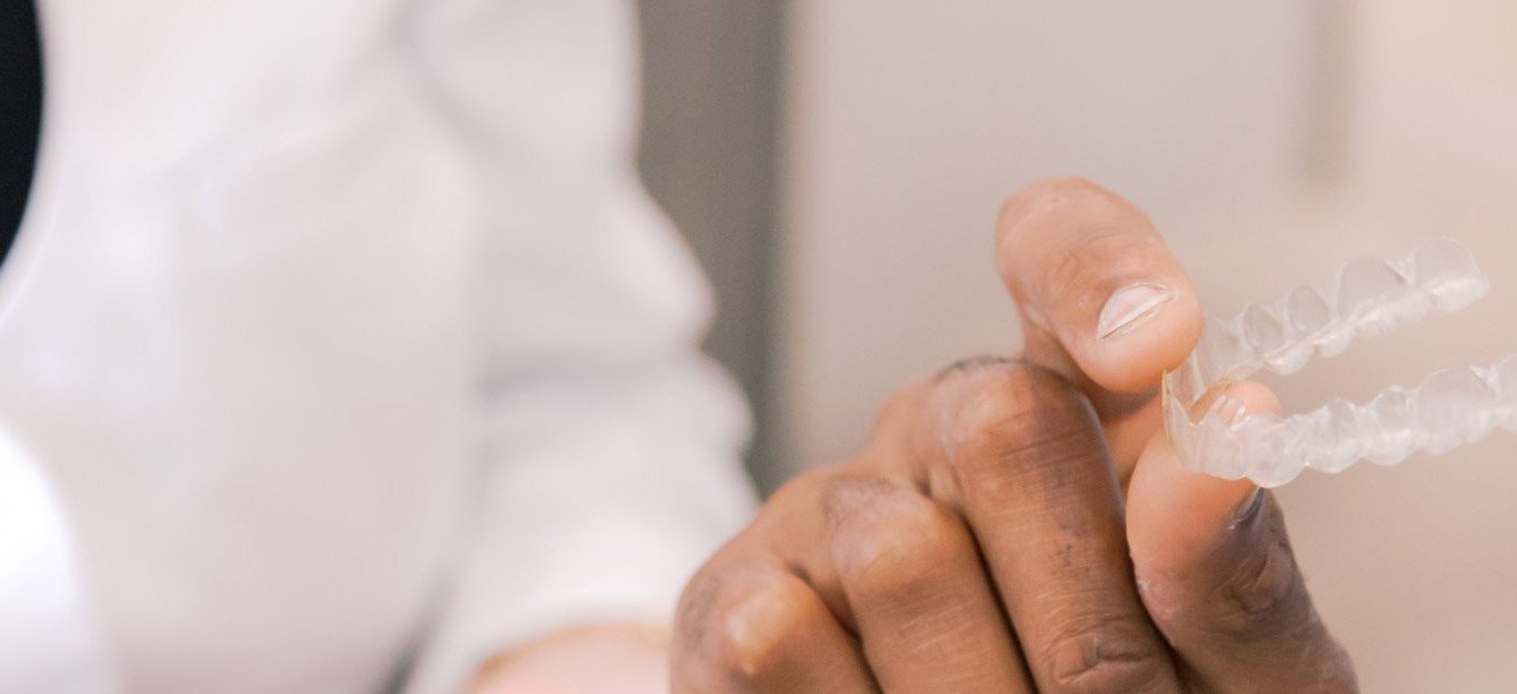 Hand holding a clear aligner from their cosmetic dentist in Lutz