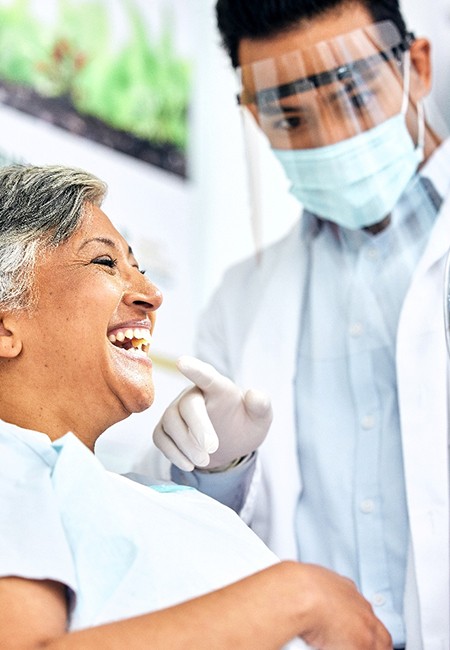 Woman smiling at reflection in dentist's mirror