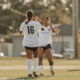 Two women high fiving on soccer field