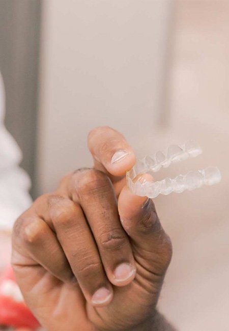 Close up of hand holding an Invisalign aligner