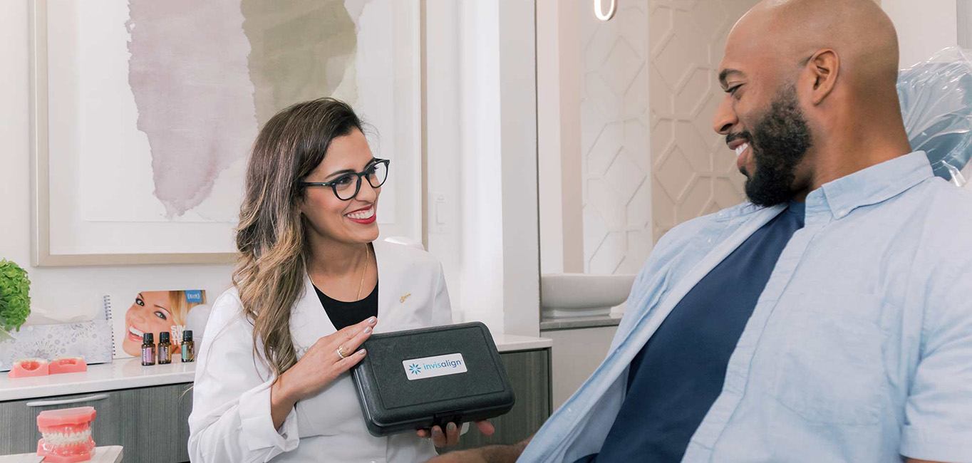 Smiling dentist showing a patient Invisalign clear aligners in Lutz