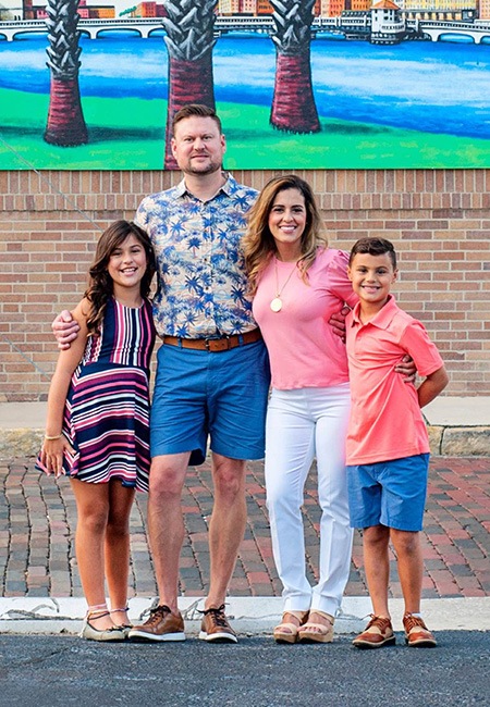 Docor Tehrani with her family in front of brick wall with mural