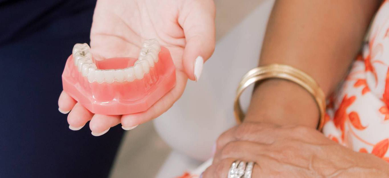 Lutz restorative dentist showing a denture to a patient