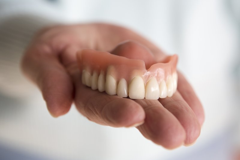 a person holding a full upper denture