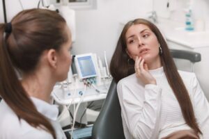 Woman in pain looking at her emergency dentist